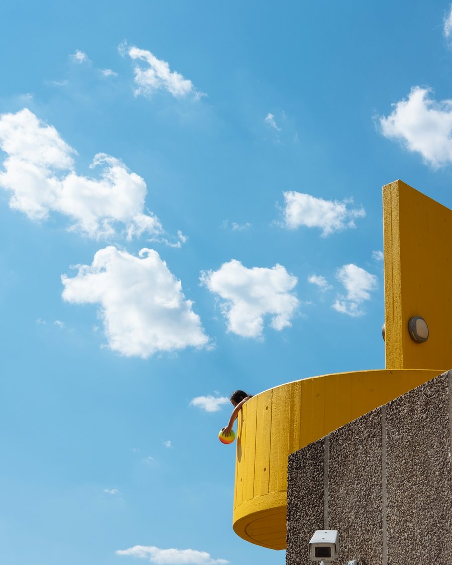 A bright yellow building against a blue sky with clouds