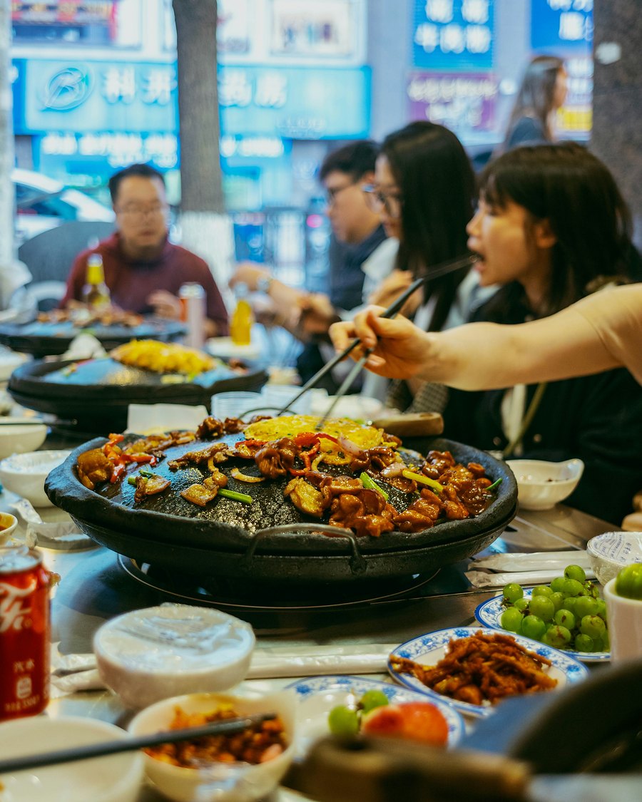 Friends sharing a big pan of food at dinner
