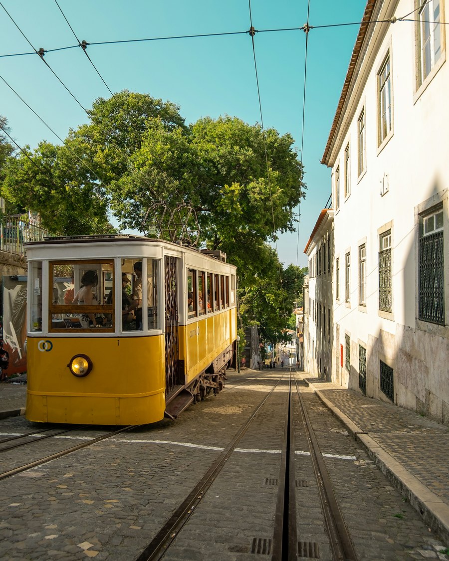 A yellow tram on a sunny street in Lisbon