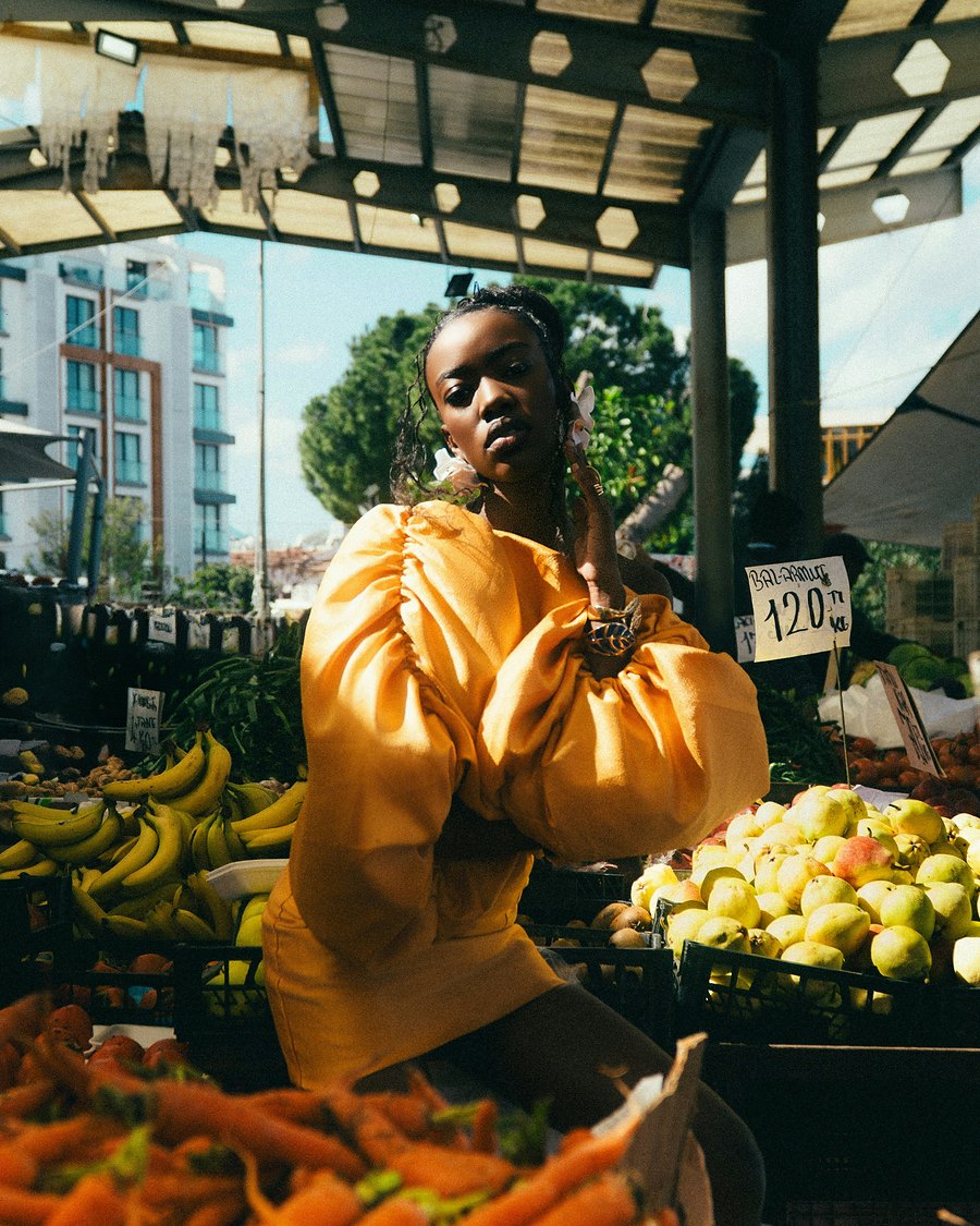 A woman in a yellow dress at a fruit and vegetable market